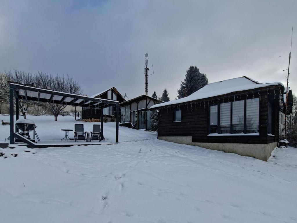 a house in the snow with a table and chairs at Coliba la Valle in Petroşani