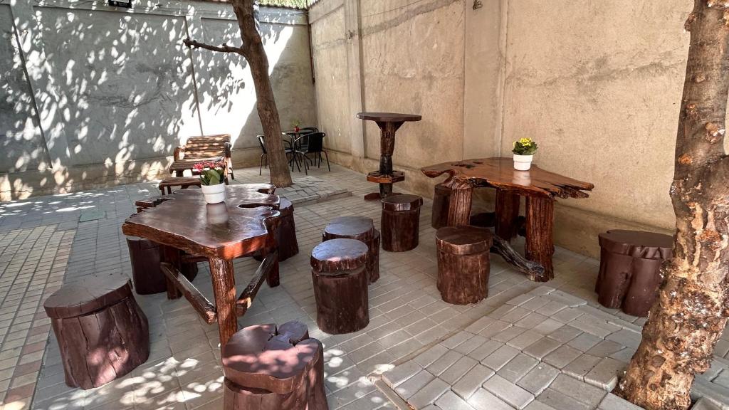 een terras met houten tafels en krukken en bomen bij Casa Joy in Boekarest