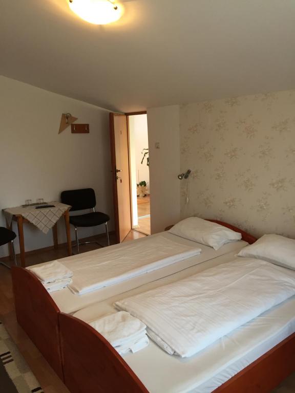 two beds in a room with a table and a chair at Pensiunea Kristine Sibiu in Sibiu