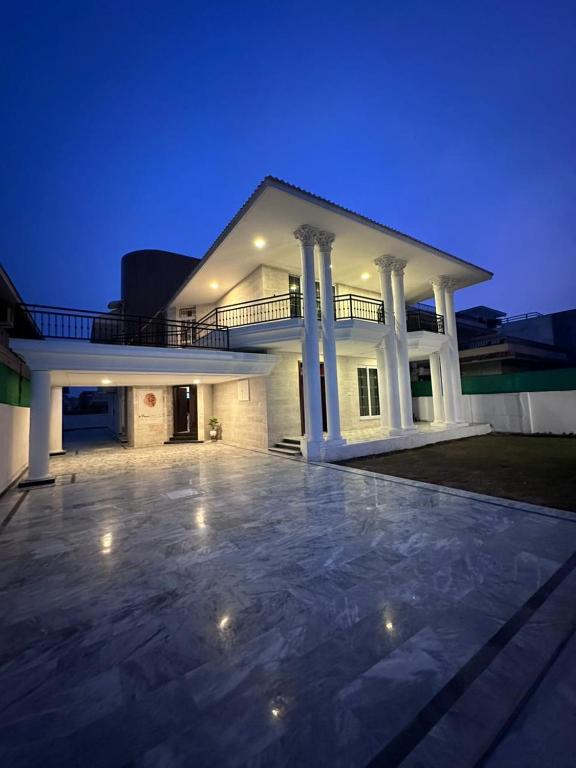 een groot wit huis met een grote patio 's nachts bij Qayaam Lodges in Islamabad