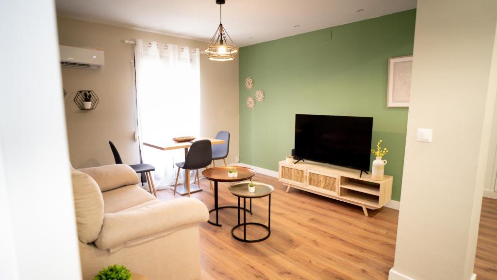 un soggiorno con un divano e una televisione di Suites Cañizares Catedral a Jaén