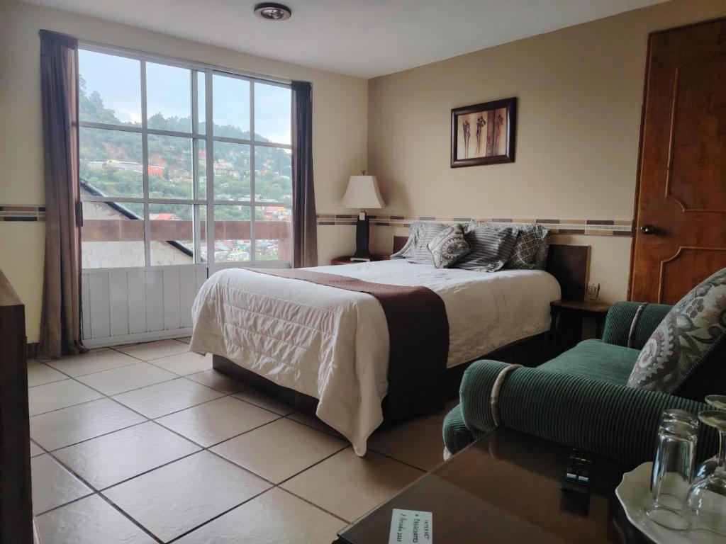 a bedroom with a bed and a couch and a window at Casa Real Cortés in Mineral del Monte