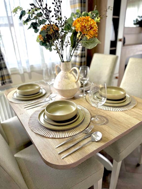 a wooden table with plates and a vase with flowers at The Lobster Pot in Ilfracombe