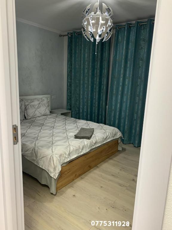a bedroom with a bed with green curtains and a chandelier at Apartament in complex rezidențial in Râmnicu Vâlcea