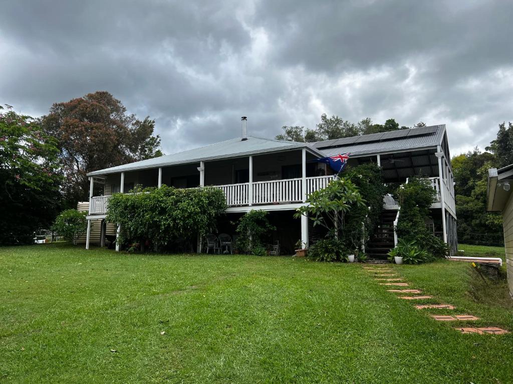 a large white house with a porch and a yard at Homestead BnB in Maudsland