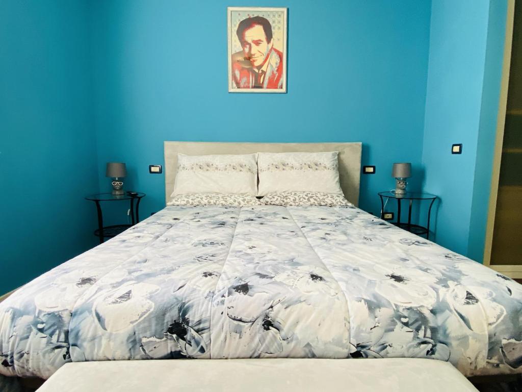 een blauwe slaapkamer met een bed met een wit dekbed bij Amici Miei Rooms in Cremona