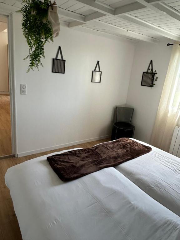 a bedroom with a white bed with a blanket on it at Gite MIRABELLE in Saint-Rémy-Boscrocourt