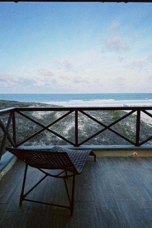 a chair on a balcony looking out at the ocean at Casa do Prãna in Guajiru