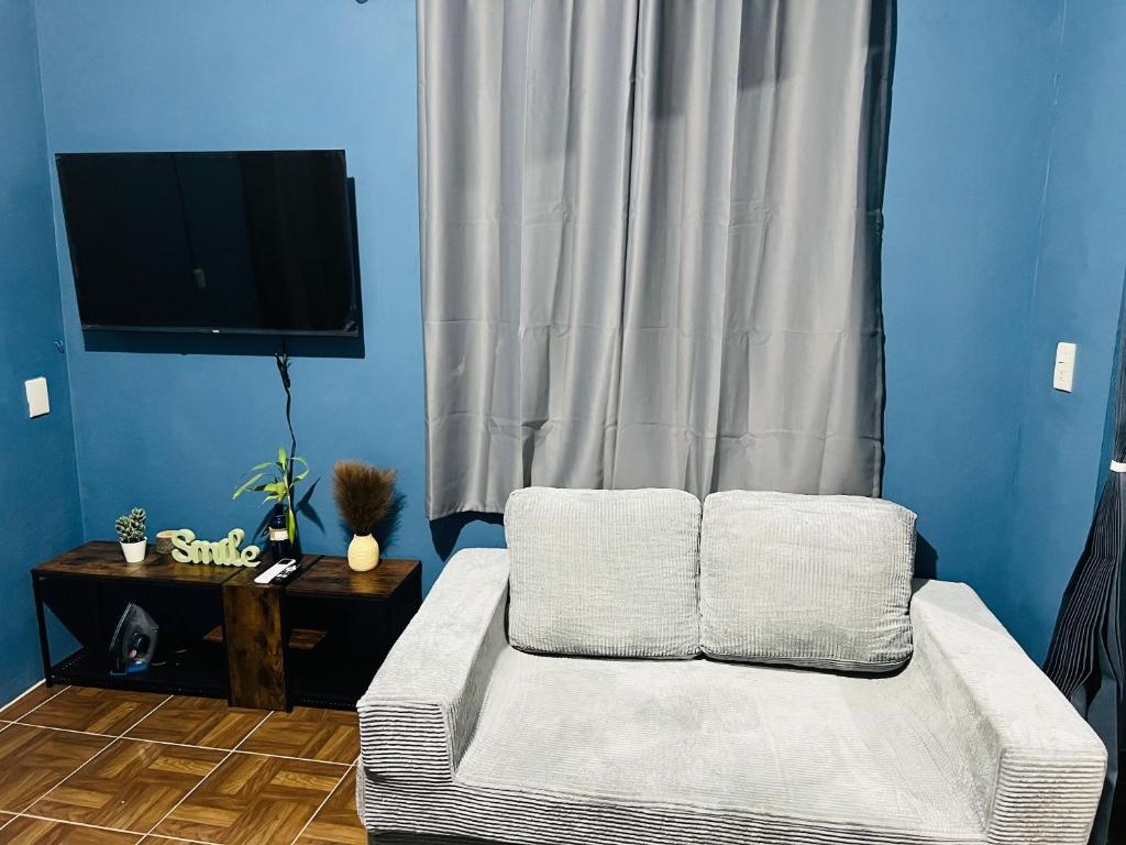 a living room with a white couch and a television at Departamento Flores in Catemaco