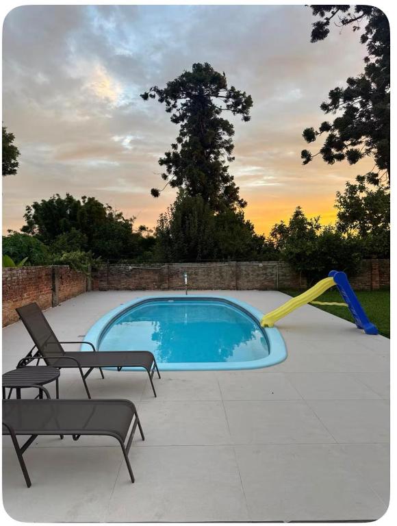 a swimming pool with two chairs and a slide at Pousada da Praça in Rosário do Sul