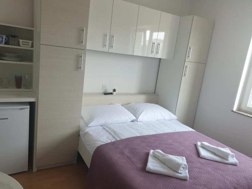 a bedroom with a bed with two white towels on it at Soba brez balkona in Stara Novalja