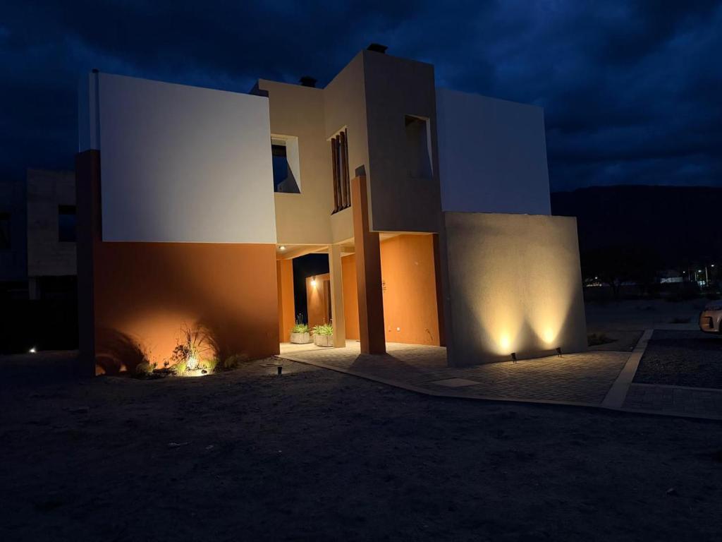 a white and orange building at night with lights at Vilaggio Magnolia in Cafayate