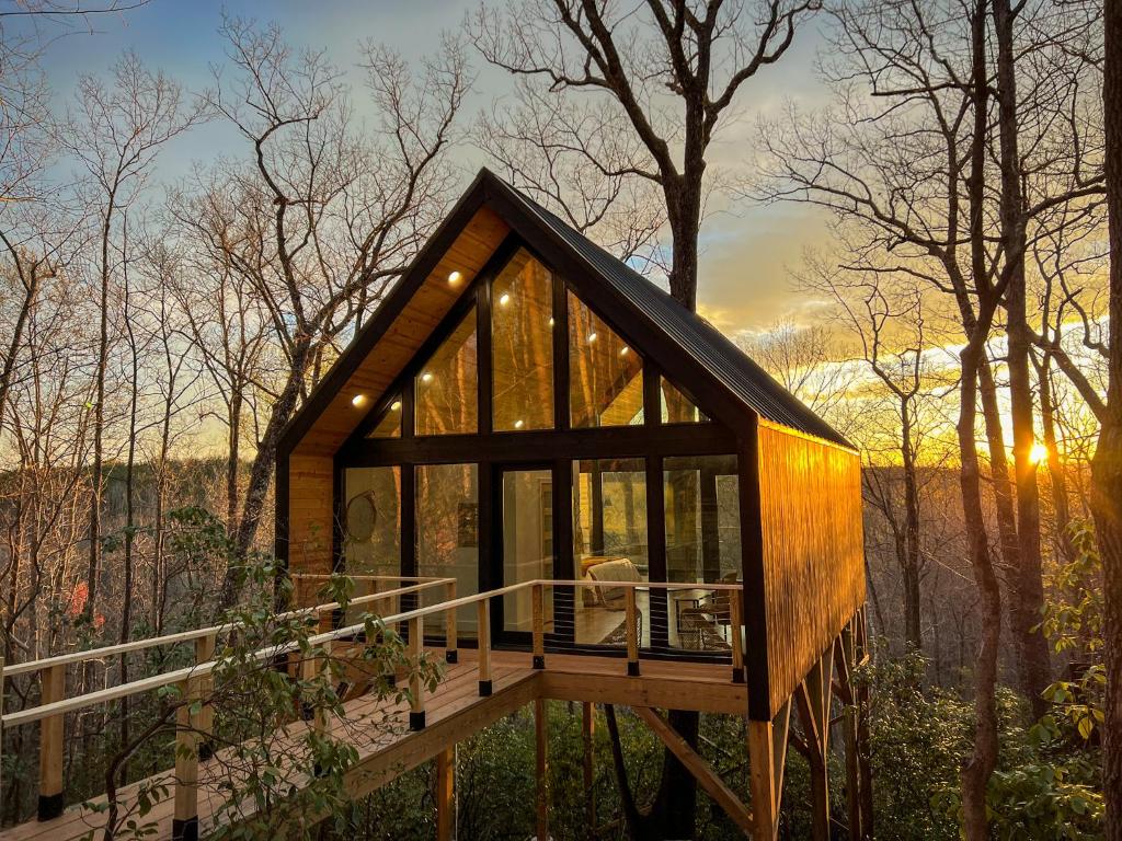 una piccola casa nel bosco con il sole che tramonta di Private Modern Treehouse Retreat in the Forest a Cross Plains