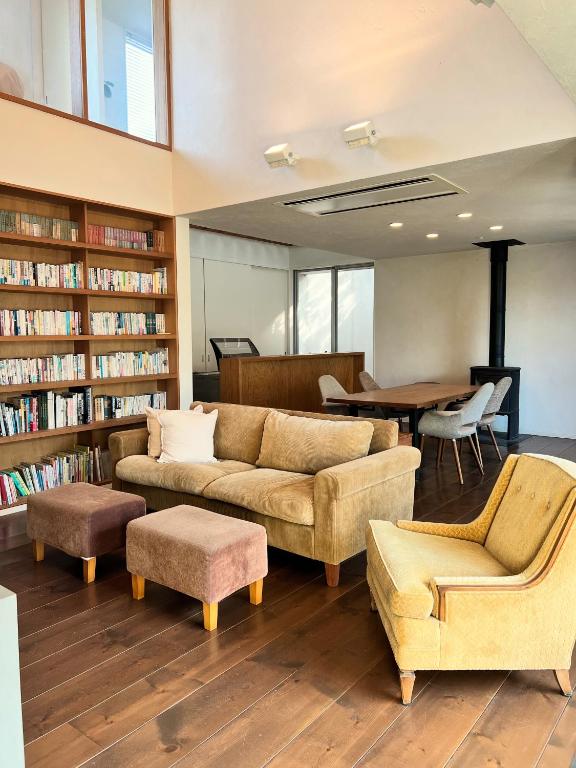 a library with a couch and chairs and a table at Urara Holiday in Sumoto