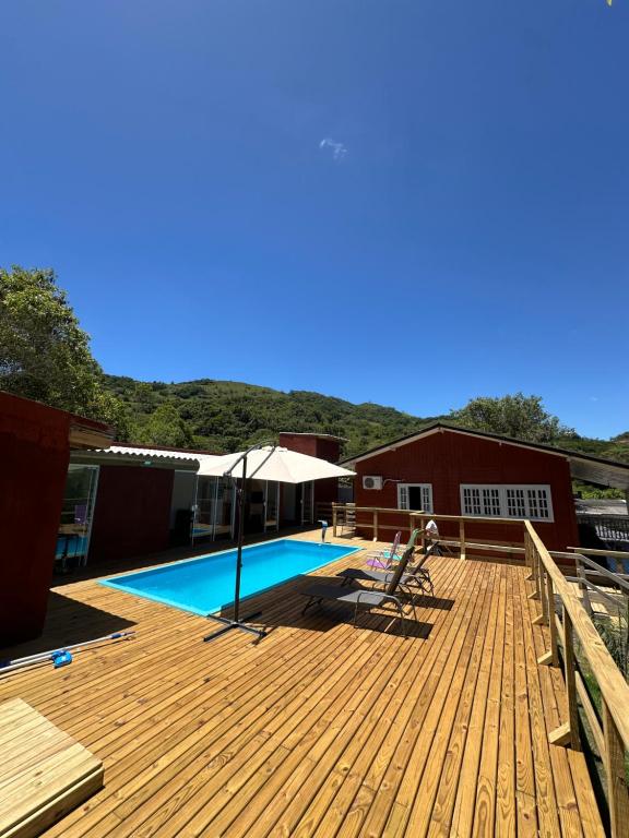 a wooden deck with a swimming pool and a house at Casa com vista para a natureza e piscina in Garopaba