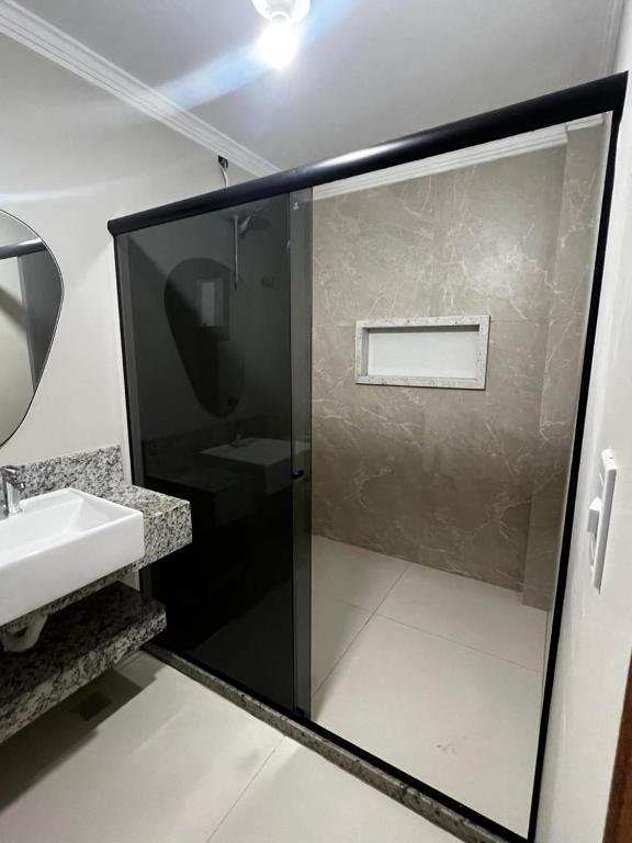 a bathroom with a glass shower and a sink at Quarto standard 9 in Guarapari