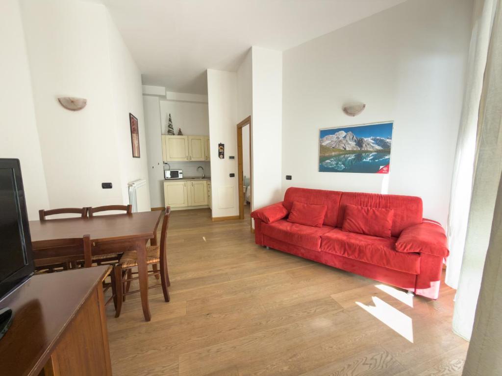 a living room with a red couch and a table at Bilocale sulle piste da sci in Pila