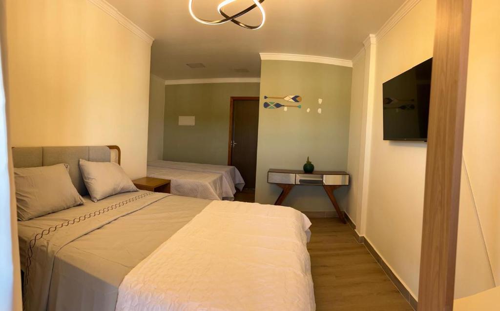 a hotel room with two beds and a television at quarto quadruplo 8 in Guarapari