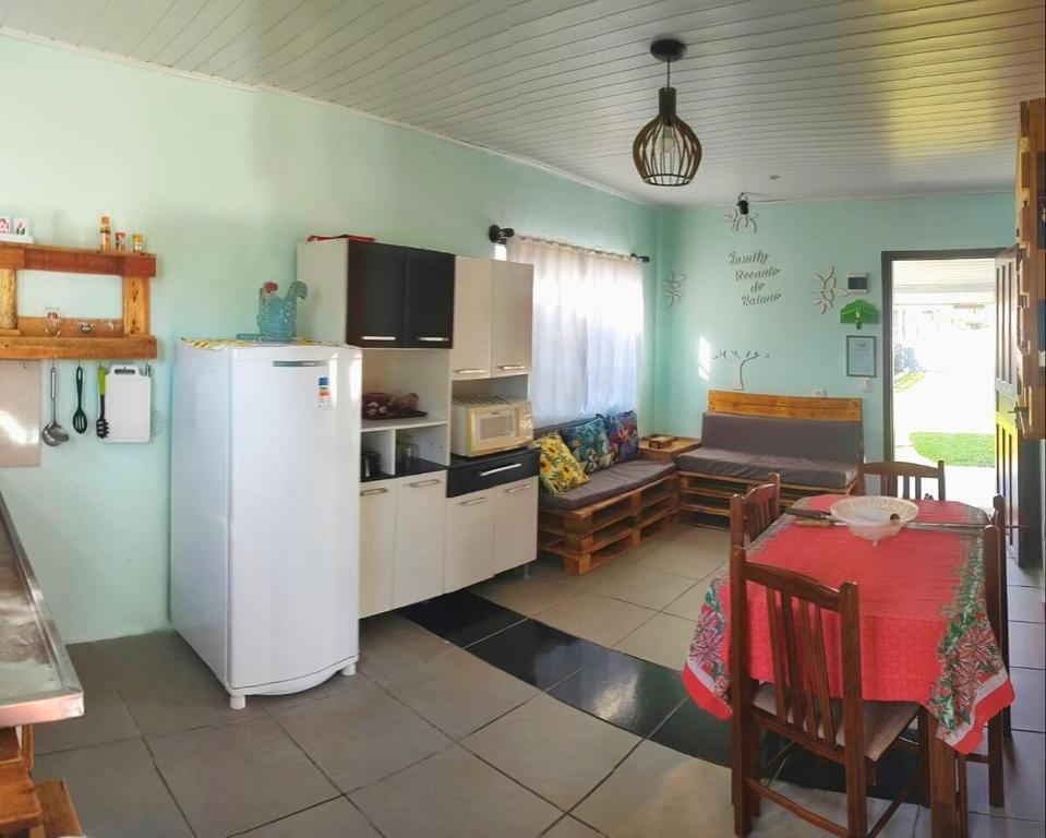 a kitchen with a refrigerator and a table and a couch at Casa Recanto do Baiano in Balneário Gaivotas