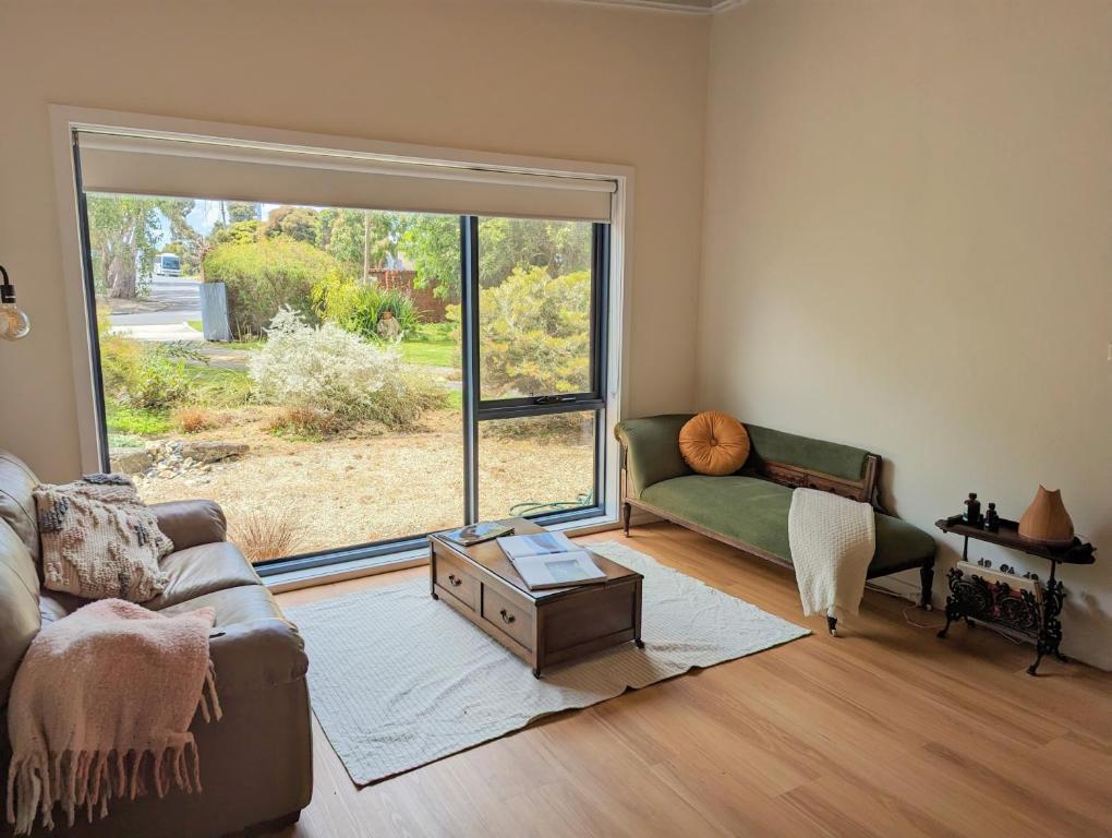 a living room with a couch and a large window at Cosy Brick Beachouse - ALL INCLUDED in Inverloch
