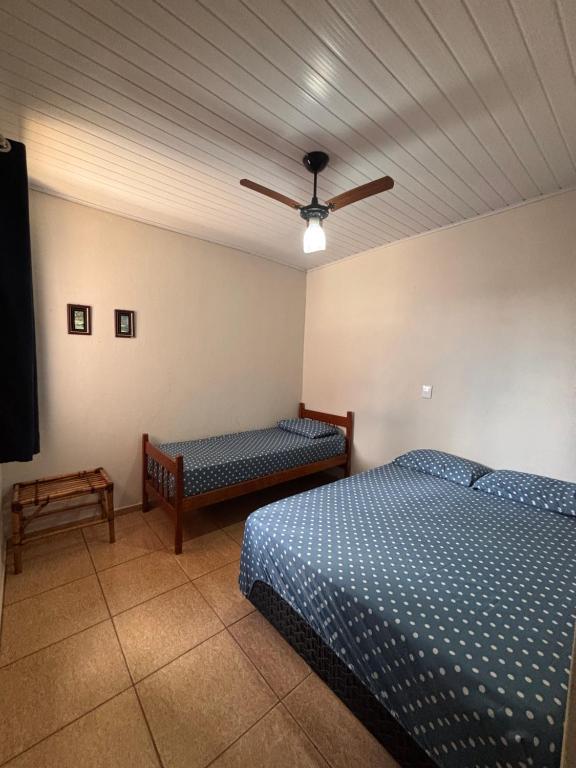 a bedroom with two beds and a ceiling fan at Recanto Lemes in Olímpia