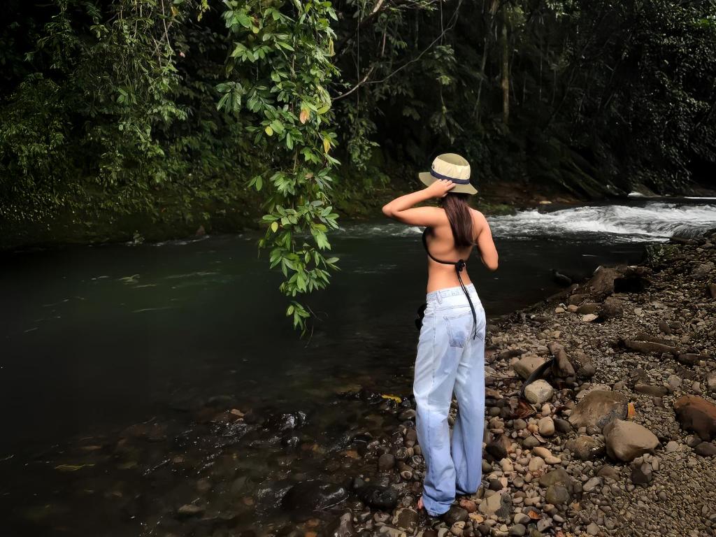 a woman standing on the rocks near a river at River Shade Inn in Tissamaharama