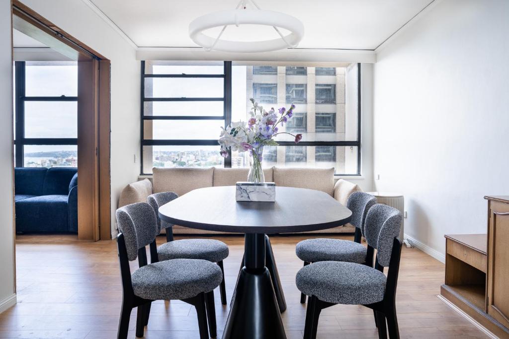 a dining room with a table and chairs with a vase of flowers at Central CBD High-Level Apartment with Views in Sydney