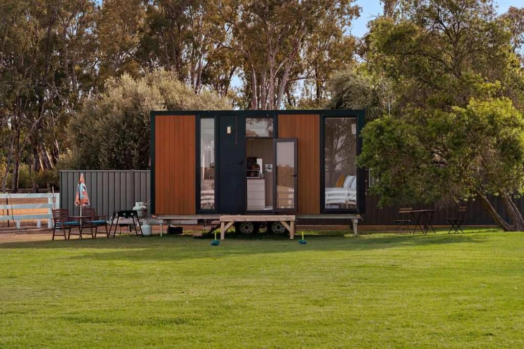una piccola casa situata su un campo erboso di Murray Haven Farm Stay by Tiny Away a Koonoomoo