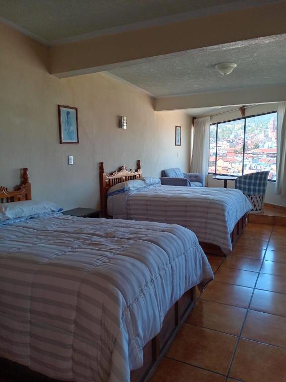 a hotel room with two beds and a window at Hotel Los Arcos in Tlalpujahua de Rayón