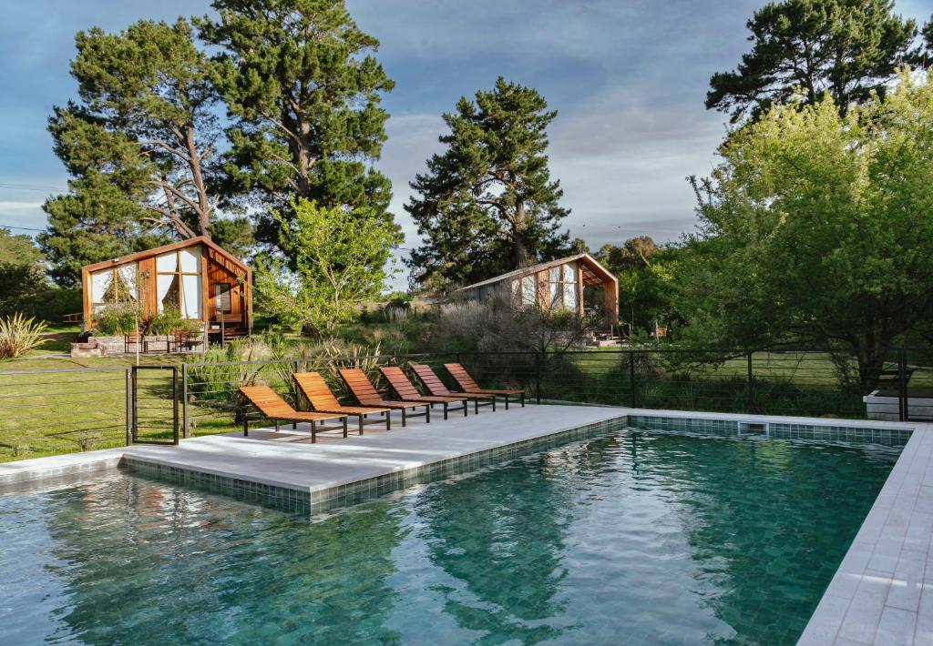 a swimming pool with chairs and a house at Cabañas Punto Prana in Tandil