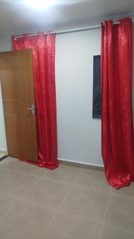 two red curtains in a room with a door at Aconchego da Maria 2! in Mangaratiba