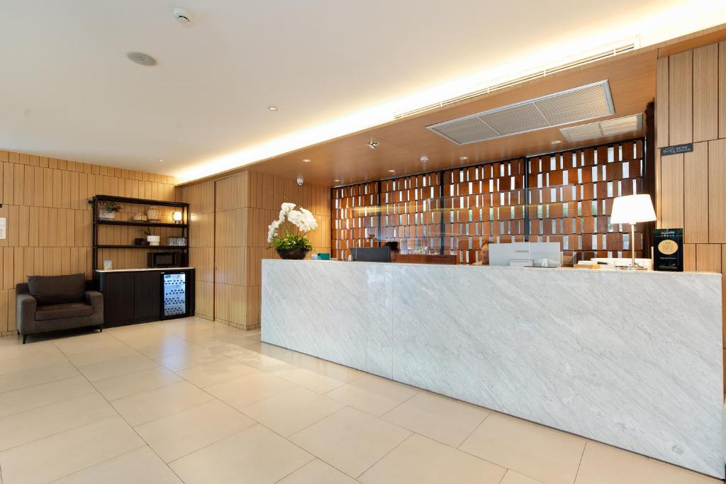 A polished reception lobby with a large white-stone front desk and wood-panelled walls.