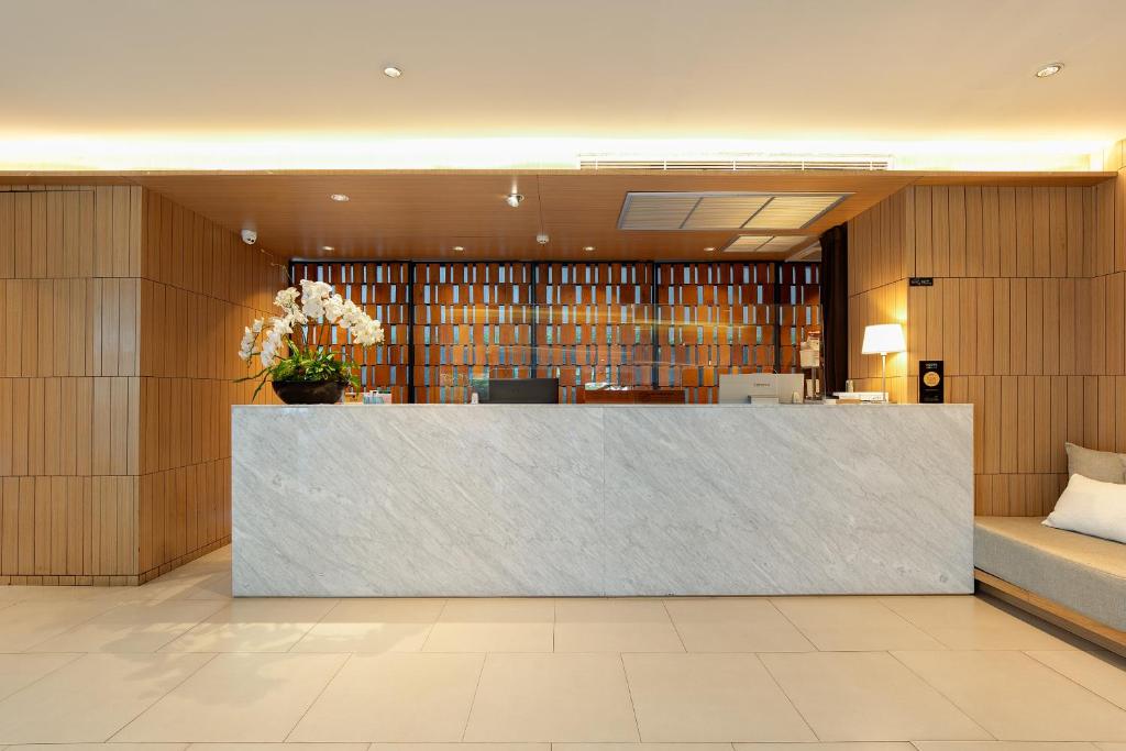 A front-facing reception desk framed by warm wood panelling and a patterned screen.