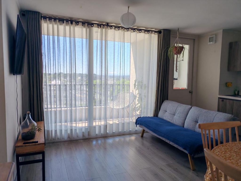 un soggiorno con un divano blu e una grande finestra di Departamento Salida Norte Temuco a Temuco