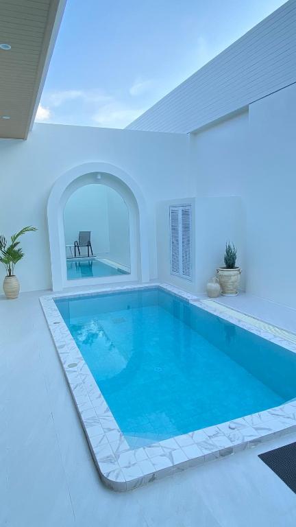 a large swimming pool in a white room with a pool at Mermayda pool villa hatyai -เมอเมดา in Hat Yai