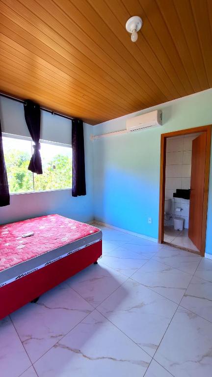 a bedroom with a red bed and a window at Paraíso Azul in Ilhéus