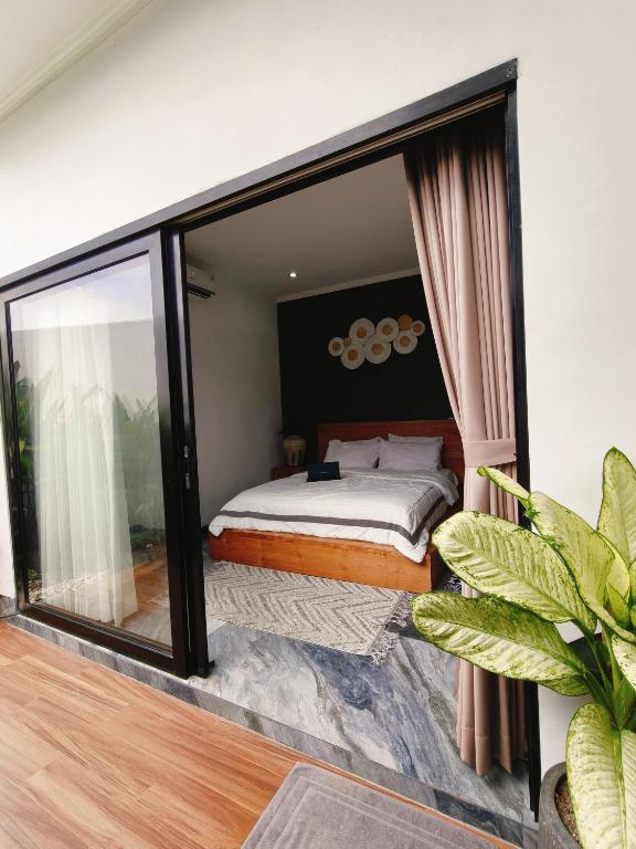 a bedroom with a bed and a large window at Santo Guesthouse in Canggu