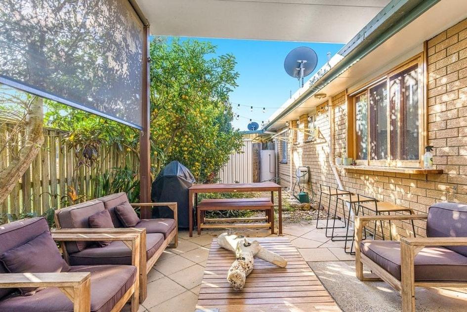 a patio with chairs and a table and a dog laying on it at The Unit Lennox Head in Lennox Head