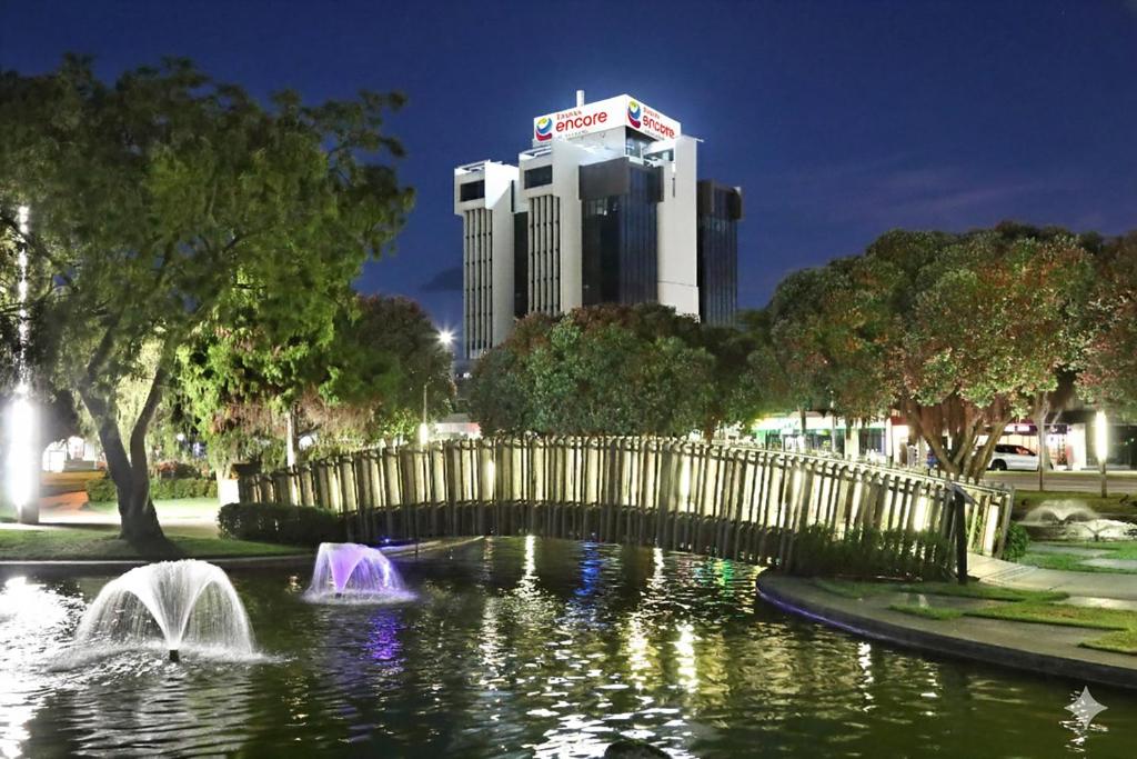 a bridge over a pond with a building in the background at Ramada Encore by Wyndham Palmerston North in Palmerston North