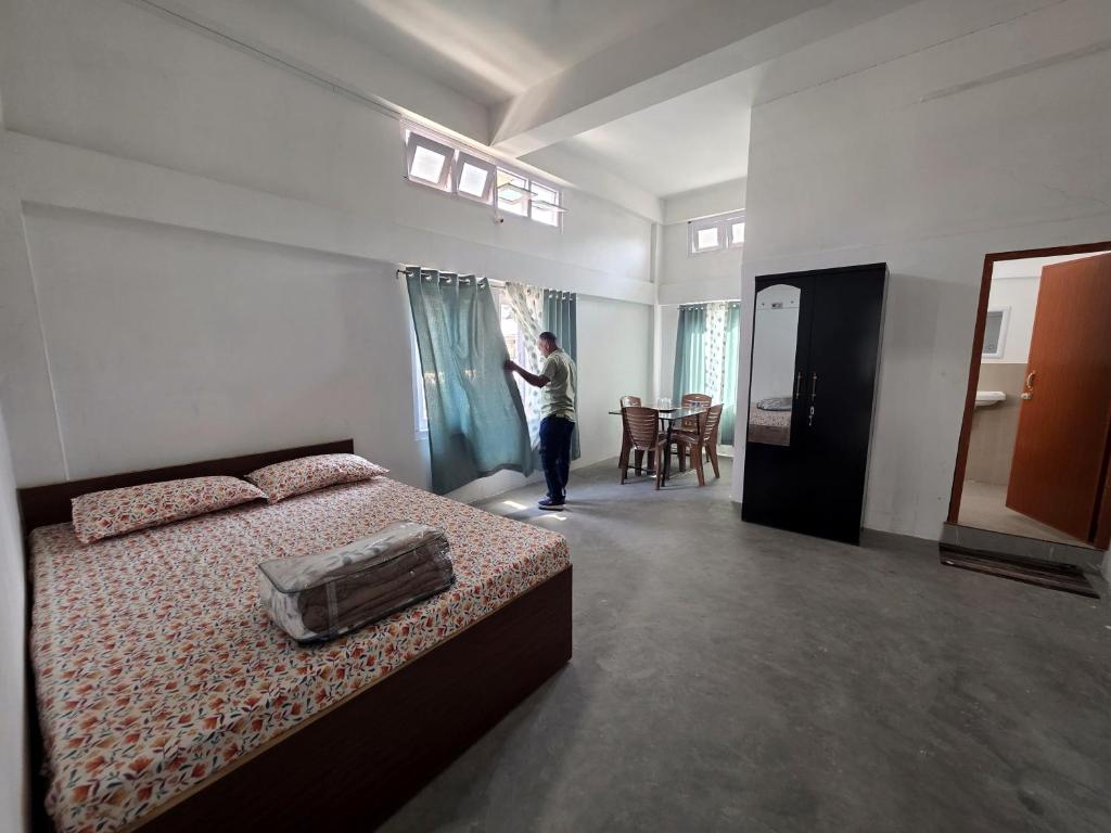 a man looking out of a window in a bedroom at The White House By Bhaskar Homestay in Dibrugarh