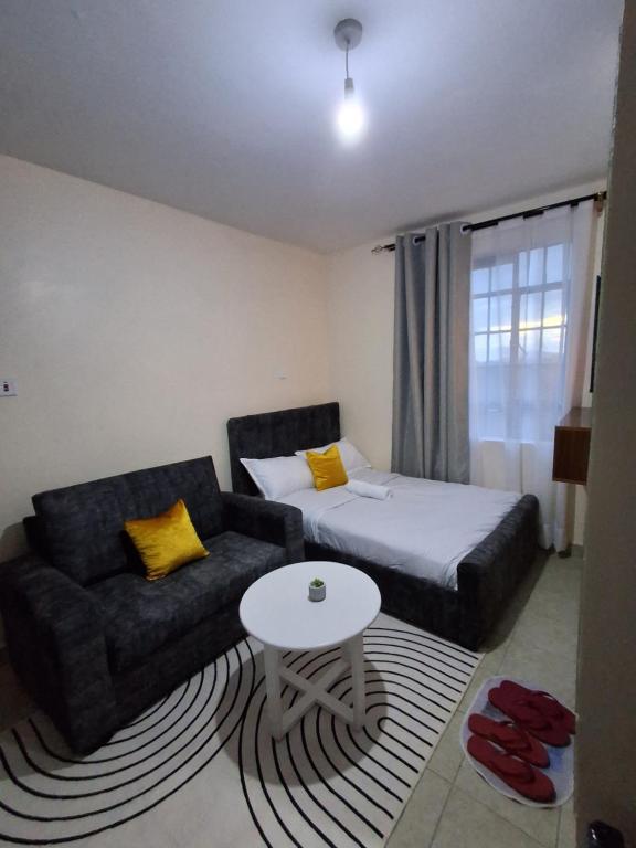 a room with a bed and a couch and a table at Machakos Town studios in Machakos