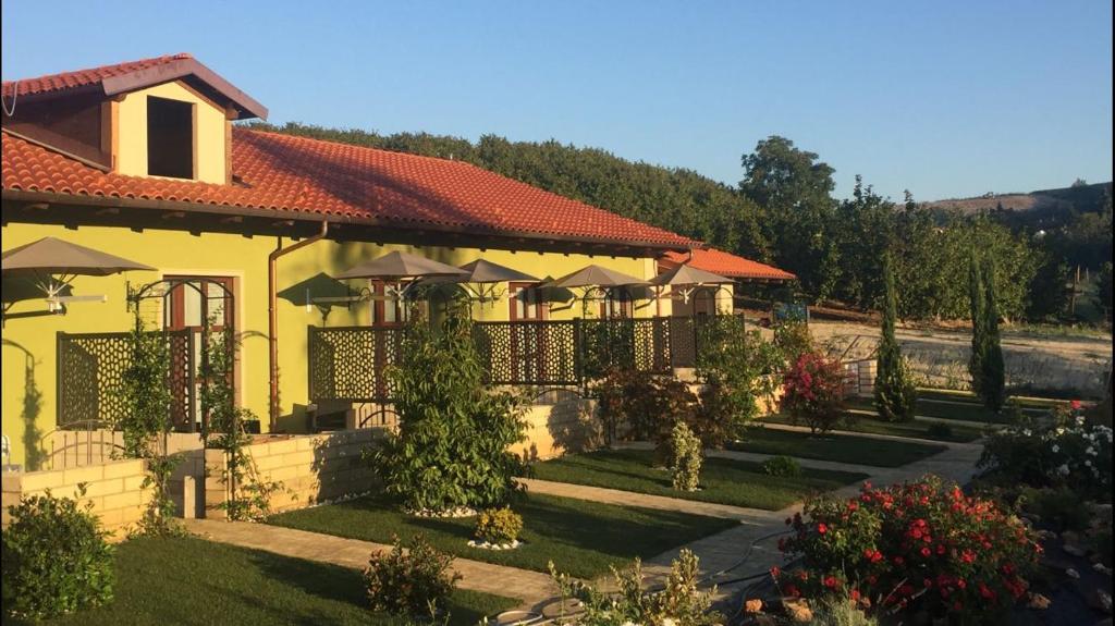 a yellow house with umbrellas in a garden at Agriturismo da Mamma in Alba