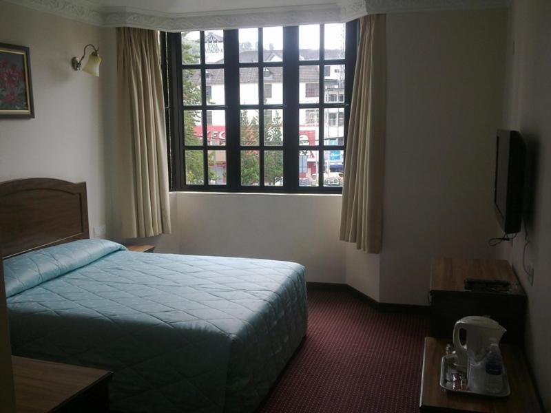 キャメロンハイランドにあるHotel Remixのベッドと窓のあるホテルの部屋
