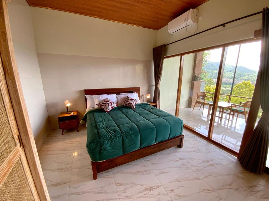 a bedroom with a green bed and a balcony at Rumah Bagus Jayanti in Sidemen