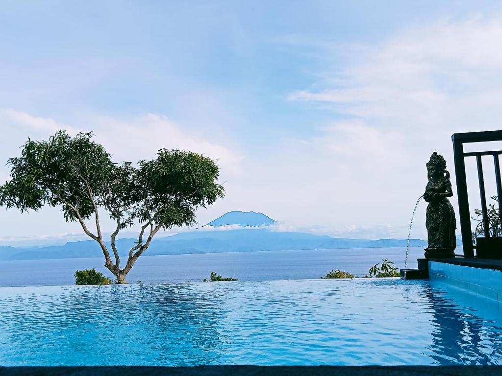 a swimming pool with a tree in the water at Bataran Garden Cottage in Nusa Penida