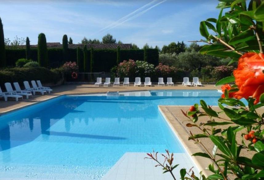 Una gran piscina con sillas blancas y flores. en Le Mazet 40, en Saint-Rémy-de-Provence