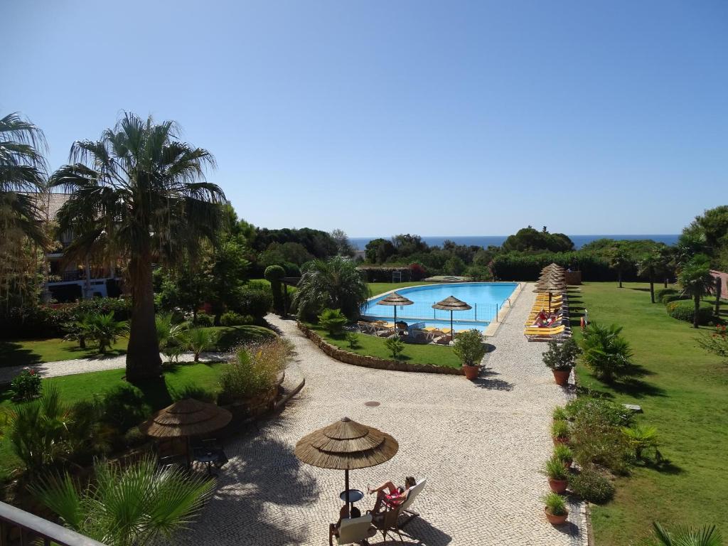 uma vista para uma piscina com guarda-sóis e um resort em Luzmar Villas na Praia da Luz