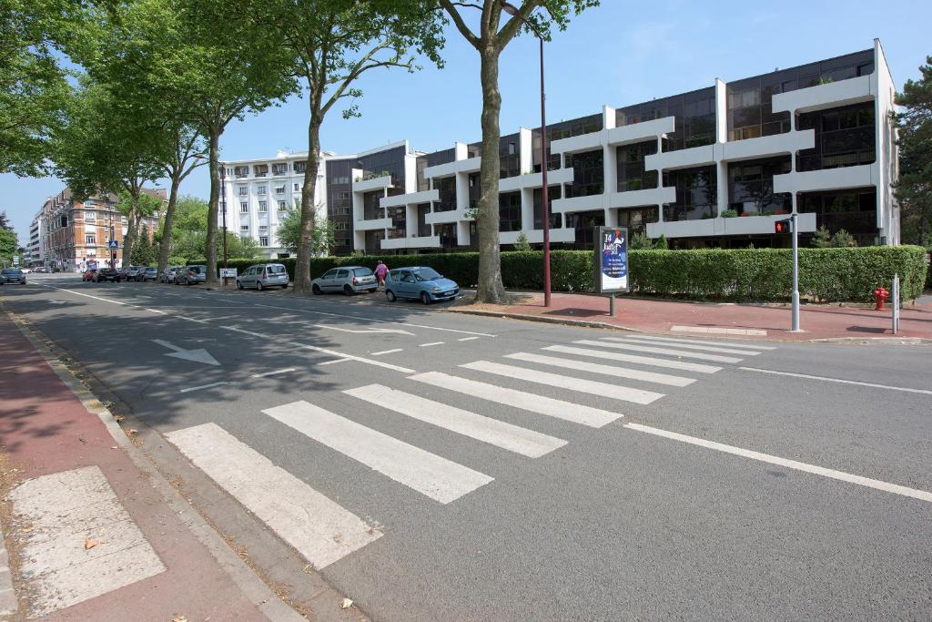 an empty street with a crosswalk in front of a building at Appartement Lille Metropolys in Marcq-en-Baroeul