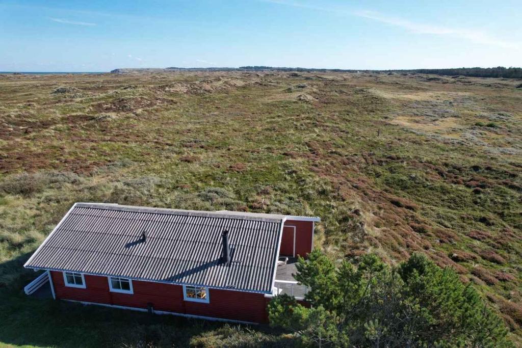 una casa rossa su una collina con un campo di Lovely Summer House On Natural Grounds a Frøstrup