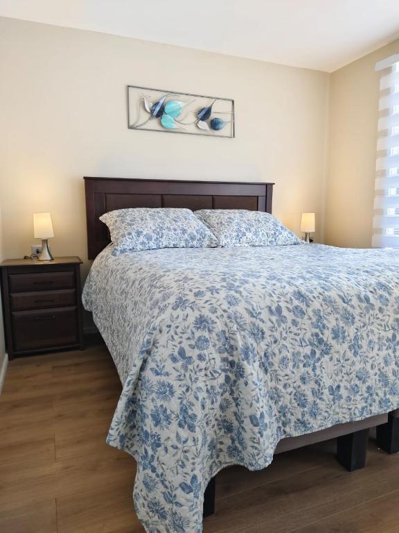a bedroom with a bed with a blue and white bedspread at Cabañas Perlas del Sur in Valdivia